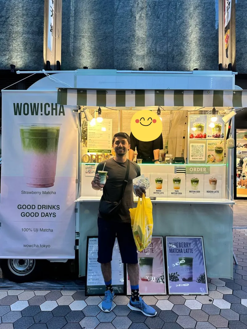Smiling tourist holding matcha latte at WOW!CHA Asakusa Rokku kitchen car