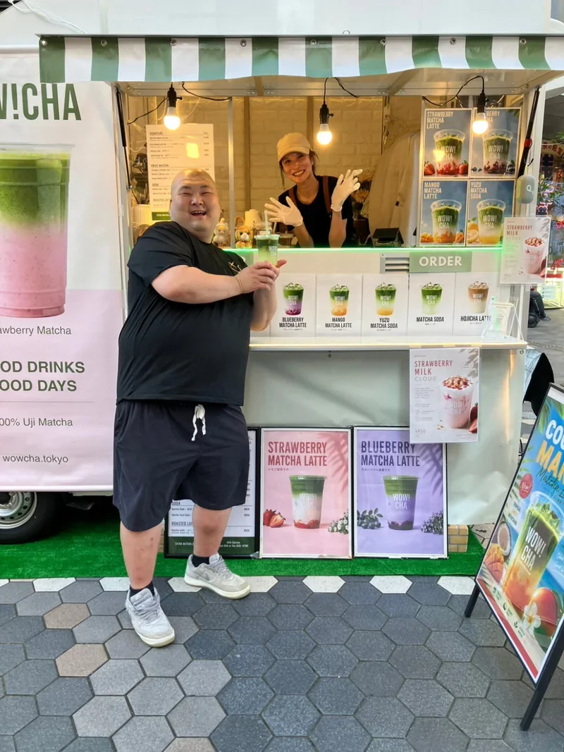 Customer holding matcha latte in front of WOW!CHA kitchen car, Asakusa Rokku Broadway