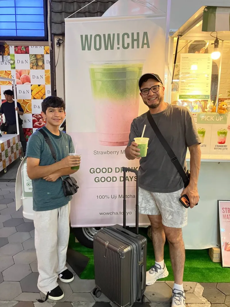 Father and son holding matcha drinks with luggage at WOW!CHA kitchen car, Asakusa Tokyo